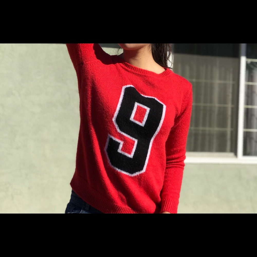 Red long sleeve sweater with a black 9 print.